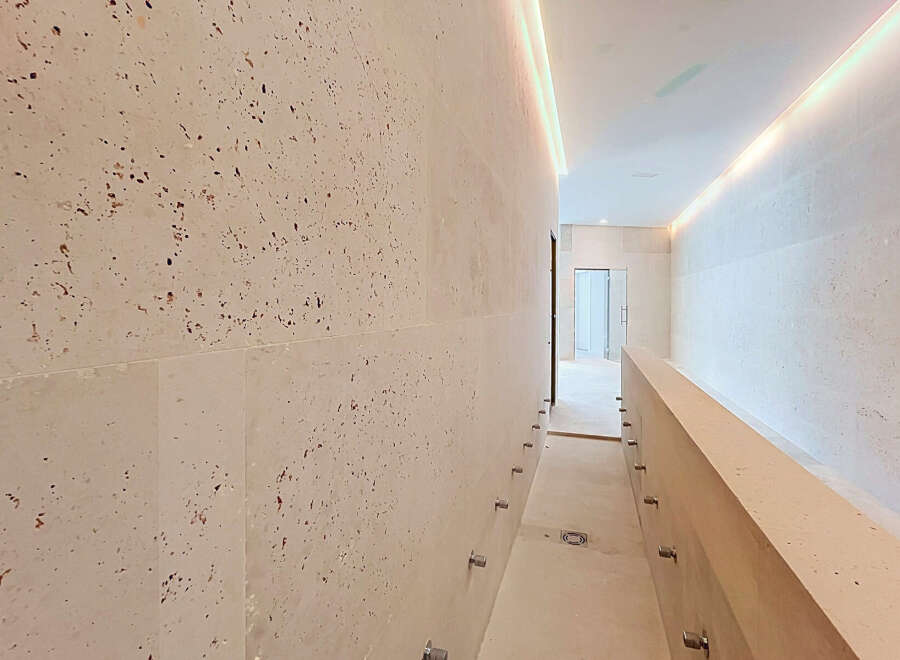 Experience modern luxury in this hallway featuring elegant travertine walls with a unique speckled pattern.