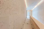 Experience modern luxury in this hallway featuring elegant travertine walls with a unique speckled pattern.