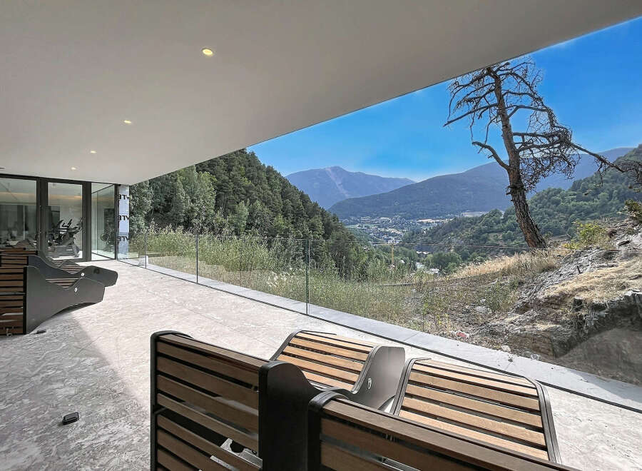Experience breathtaking mountain views from this modern property, featuring a spacious outdoor patio with comfortable seating.