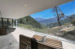 Experience breathtaking mountain views from this modern property, featuring a spacious outdoor patio with comfortable seating.