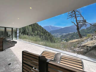 Experience breathtaking mountain views from this modern property, featuring a spacious outdoor patio with comfortable seating.
