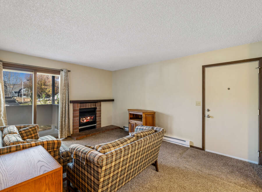 Cozy up in this charming living room featuring a brick fireplace, perfect for those chilly evenings.