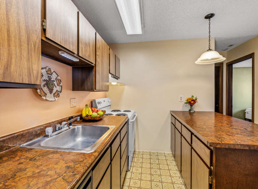 This charming kitchen features warm wood cabinetry and a spacious countertop, perfect for meal preparation and entertaining.