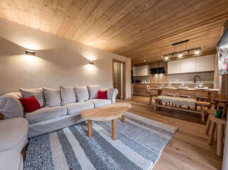 Experience the warmth of this inviting living space, featuring a cozy sofa adorned with vibrant red cushions.