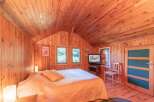 This cozy bedroom boasts a warm, inviting atmosphere with its wood-paneled walls and ceiling.