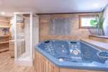 Relax and unwind in this luxurious spa-like bathroom! Featuring a stunning blue hot tub, a modern shower, and elegant wooden accents, this space is designed for ultimate comfort and relaxation.