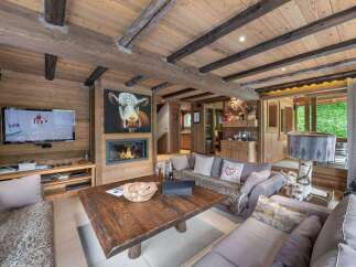 Experience rustic charm in this stunning chalet, featuring a cozy fireplace and a unique cow painting.