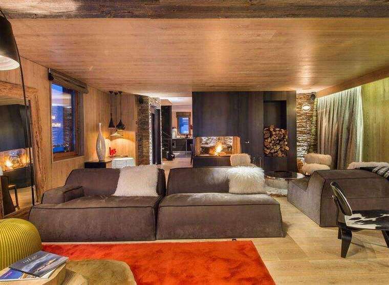 Experience luxury living in this stunning chalet, featuring a cozy living room with a fireplace and plush seating.