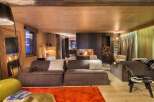 Experience luxury living in this stunning chalet, featuring a cozy living room with a fireplace and plush seating.