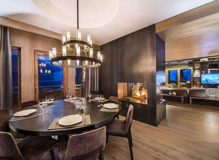Experience luxury living in this stunning property, featuring a sophisticated dining area with a modern chandelier and a cozy fireplace.