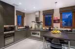 This modern kitchen boasts sleek, dark cabinetry and stainless steel appliances, creating a sophisticated and functional space.