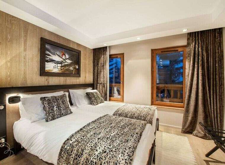Experience luxury mountain living in this elegantly appointed bedroom featuring two comfortable twin beds, perfect for a restful night's sleep.