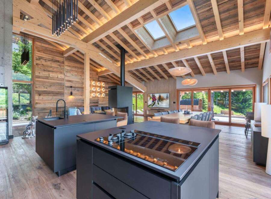 Experience luxury living in this stunning chalet, featuring a modern kitchen with sleek countertops and a built-in cooktop.