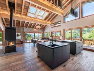 Experience luxury living in this stunning property, featuring a modern kitchen with sleek black countertops and a cozy fireplace.