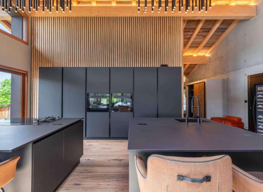 This modern kitchen boasts sleek, dark cabinetry and countertops, creating a sophisticated and contemporary aesthetic.