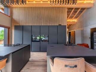 This modern kitchen boasts sleek, dark cabinetry and countertops, creating a sophisticated and contemporary aesthetic.