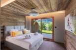 Experience luxury in this stunning bedroom featuring a cozy wooden ceiling and walls.