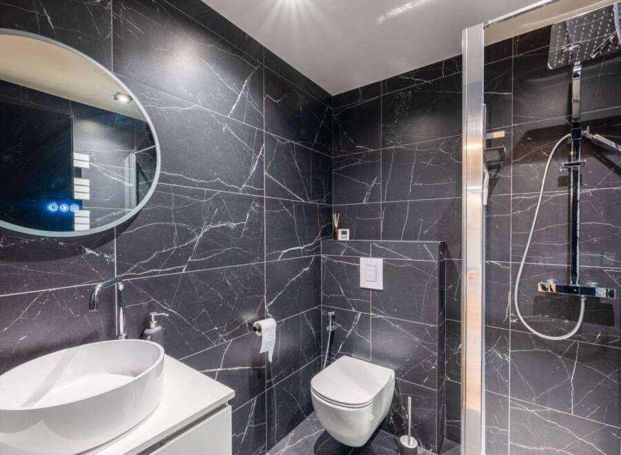 Step into luxury with this stunning bathroom featuring sleek black marble tiles.
