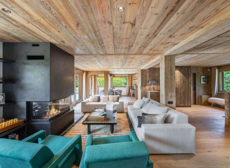 Experience luxury living in this stunning property featuring a modern fireplace, cozy seating areas, and a warm wooden interior.