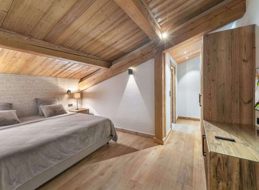 Experience the charm of this stunning bedroom, featuring a warm wooden ceiling and flooring that create a cozy ambiance.