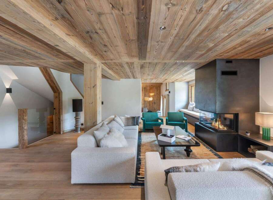 Experience luxury living in this stunning property, featuring a cozy living room with a modern fireplace and a warm wooden ceiling.