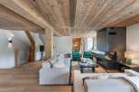 Experience luxury living in this stunning property, featuring a cozy living room with a modern fireplace and a warm wooden ceiling.