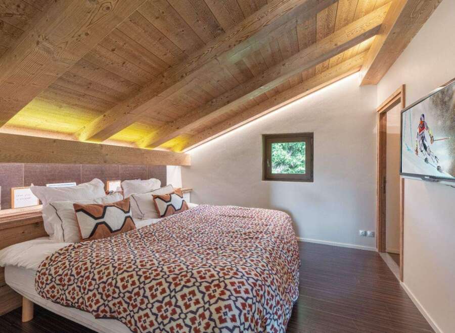 Experience the charm of this cozy bedroom featuring a unique wooden ceiling and a comfortable bed with stylish pillows.