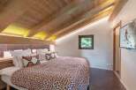 Experience the charm of this cozy bedroom featuring a unique wooden ceiling and a comfortable bed with stylish pillows.