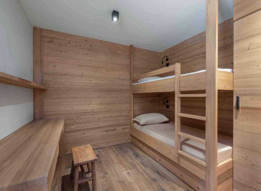 This cozy bedroom features custom wood paneling and a built-in bunk bed, perfect for a vacation home or rental property.