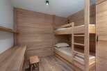 This cozy bedroom features custom wood paneling and a built-in bunk bed, perfect for a vacation home or rental property.