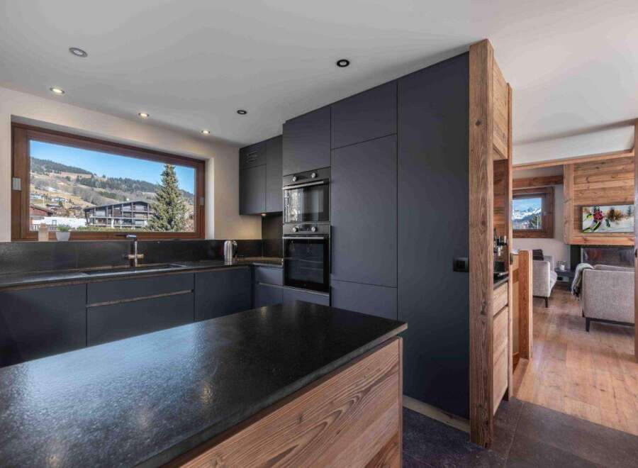 Experience modern luxury in this stunning kitchen, featuring sleek dark cabinetry and a spacious island with a natural wood base.