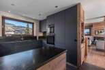 Experience modern luxury in this stunning kitchen, featuring sleek dark cabinetry and a spacious island with a natural wood base.