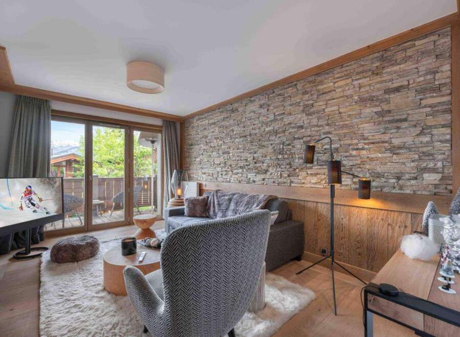 Experience luxury living in this stunning property, featuring a cozy living room with a stone wall and a modern floor lamp.