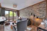 Experience luxury living in this stunning property, featuring a cozy living room with a stone wall and a modern floor lamp.