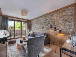 Experience luxury living in this stunning property, featuring a cozy living room with a stone wall and a modern floor lamp.