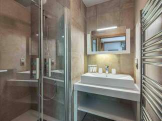This modern bathroom features a sleek glass shower enclosure and a stylish vanity with a rectangular sink.