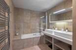 This modern bathroom features a sleek design with a double vanity and a luxurious bathtub.