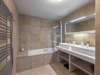 This modern bathroom features a sleek design with a double vanity and a luxurious bathtub.