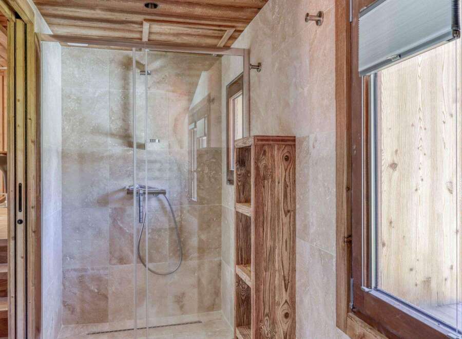 Step into luxury with this stunning bathroom featuring a sleek glass shower enclosure and elegant wooden accents.