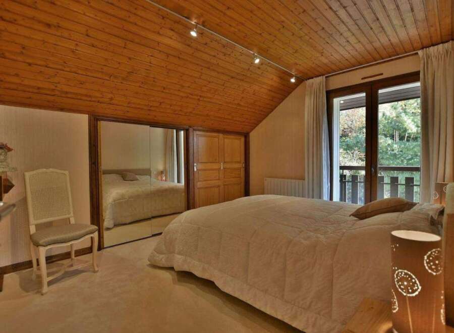 Discover the charm of this inviting bedroom, featuring a warm wooden ceiling and ample natural light.
