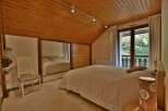 Discover the charm of this inviting bedroom, featuring a warm wooden ceiling and ample natural light.