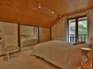 Discover the charm of this inviting bedroom, featuring a warm wooden ceiling and ample natural light.