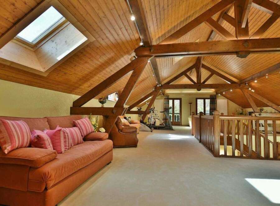 This stunning property boasts a unique architectural design with exposed wooden beams and a vaulted ceiling, creating an open and airy atmosphere.