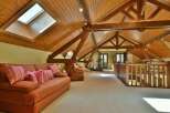 This stunning property boasts a unique architectural design with exposed wooden beams and a vaulted ceiling, creating an open and airy atmosphere.