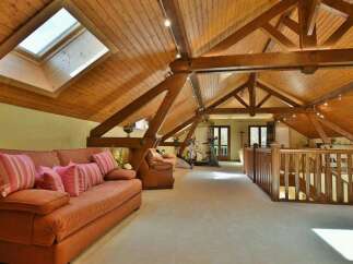 This stunning property boasts a unique architectural design with exposed wooden beams and a vaulted ceiling, creating an open and airy atmosphere.