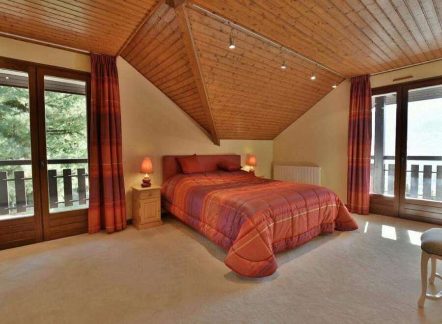 This cozy bedroom features a warm, inviting atmosphere with its wooden ceiling and soft carpet.
