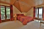 This cozy bedroom features a warm, inviting atmosphere with its wooden ceiling and soft carpet.