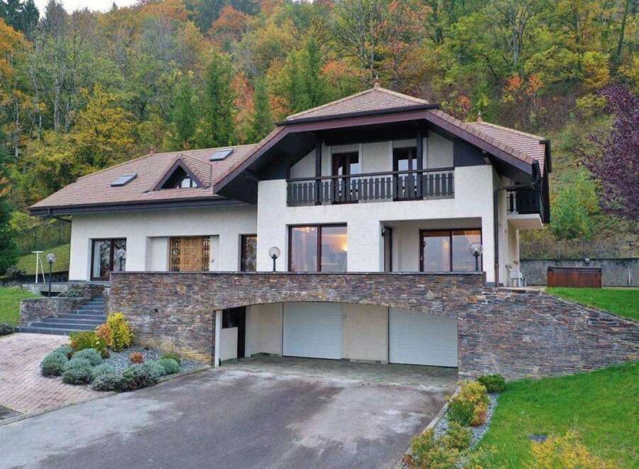 This stunning property boasts a modern design with a touch of rustic charm, featuring a beautiful stone facade and a well-manicured lawn.
