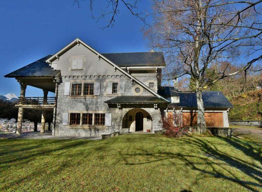 This stunning property boasts a unique architectural design with a stone facade and a charming balcony.