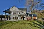 This stunning property boasts a unique architectural design with a stone facade and a charming balcony.